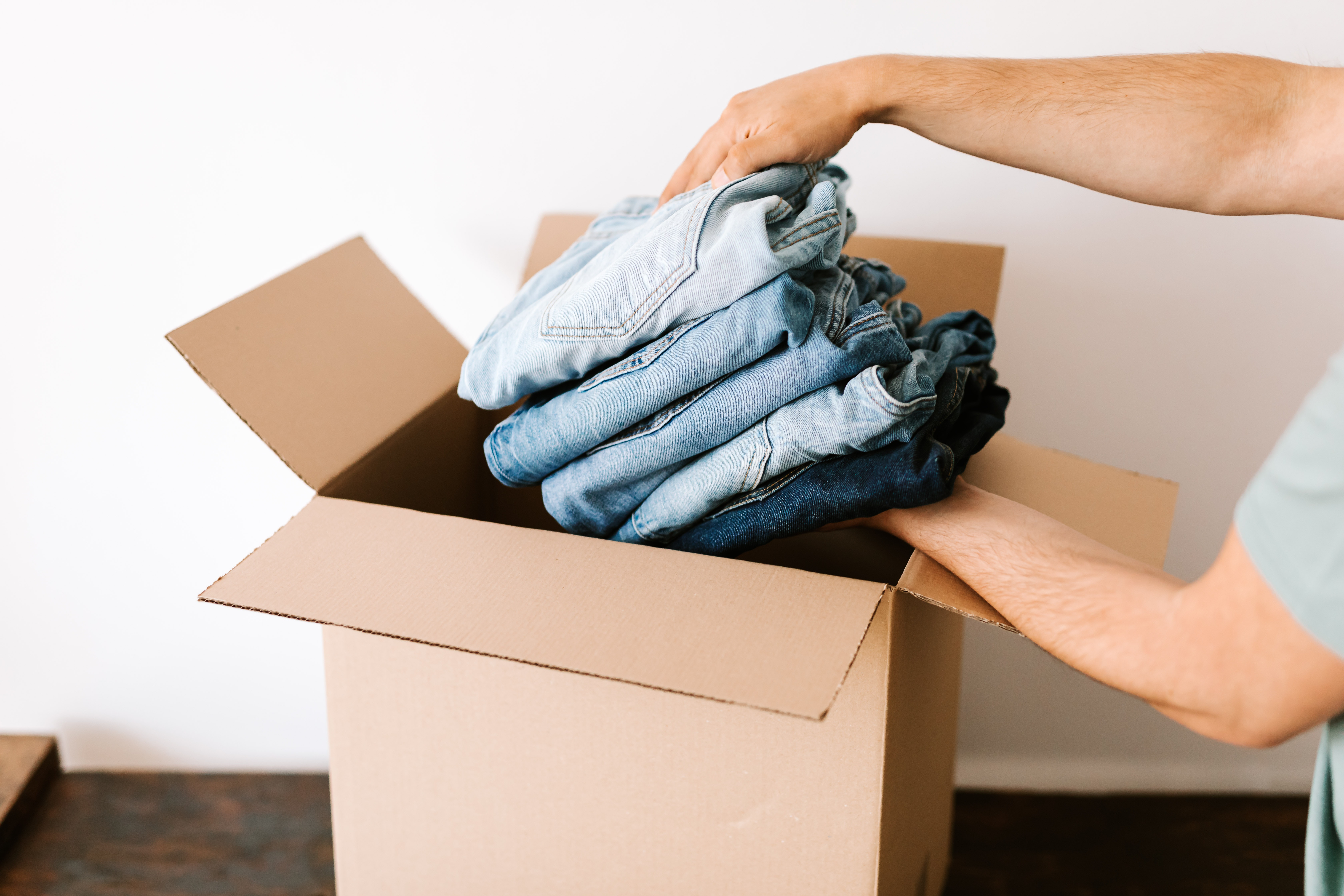 person packing jeans into a box