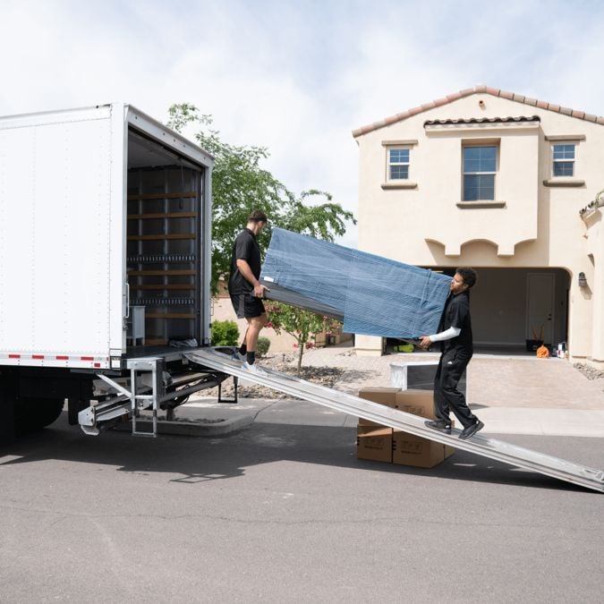 two members of Moving By Design loading furniture to a moving truck