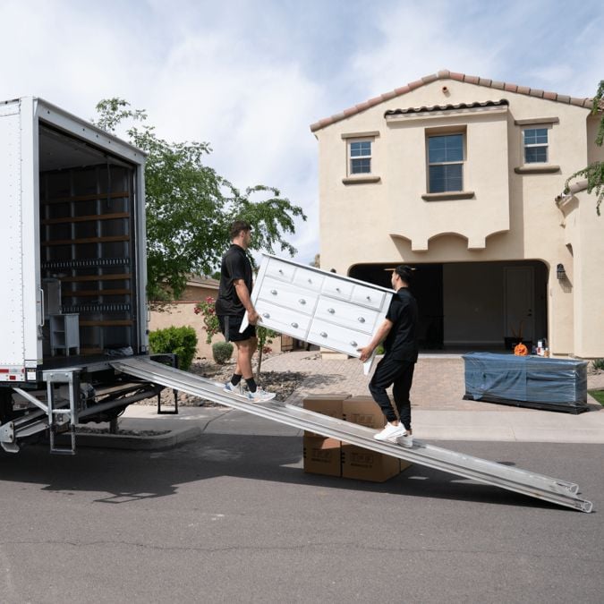 Moving By Design members loading a dresser into a moving truck