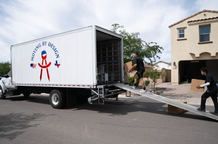 two members of Moving By Design loading boxes