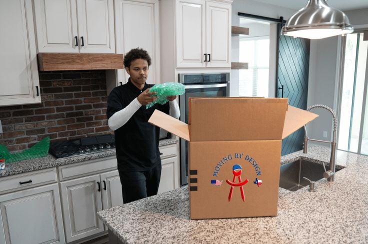 a member of Moving By Design packing things for a move